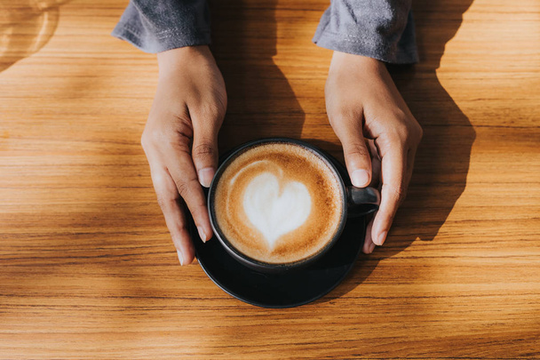 Mano di donna con tazza di caffè sul tavolo in legno nel caffè
. - Foto, immagini