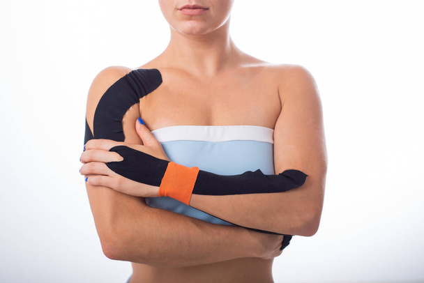白い背景にキネツィオテープを持つ女性の肩。関節および靭帯のスポーツ傷害のための代替薬。肩と手首の痛みの医療記録を持つ若いスポーツウーマン. - 写真・画像