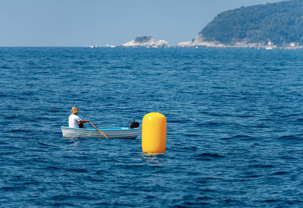 Man in the middle of the sea on a rowboat - Liguria Italy - Photo, Image