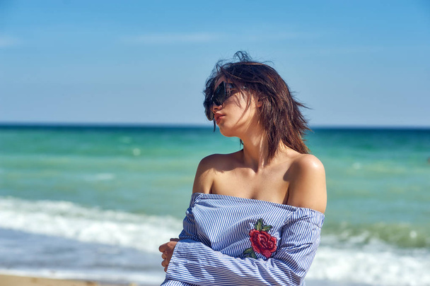 Hermosa niña sana en gafas de sol de moda en la playa. La modelo lleva una blusa y una falda
 - Foto, imagen