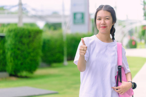 Asiático joven chica adolescente sonriendo con el pulgar hasta al aire libre brillante día
 - Foto, imagen