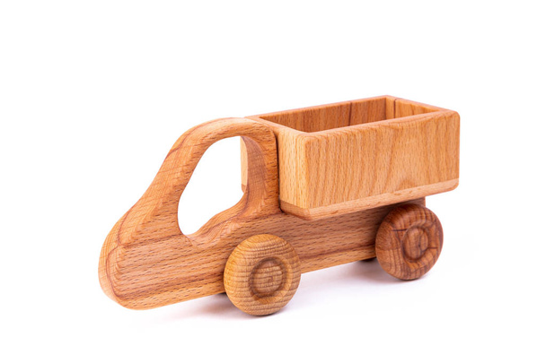 Foto van een houten auto van beukenhout. Speelgoed gemaakt van hout retro truck op een witte geïsoleerde achtergrond. Een speeltje voor het vermaken van kinderen en rust ouders - Foto, afbeelding