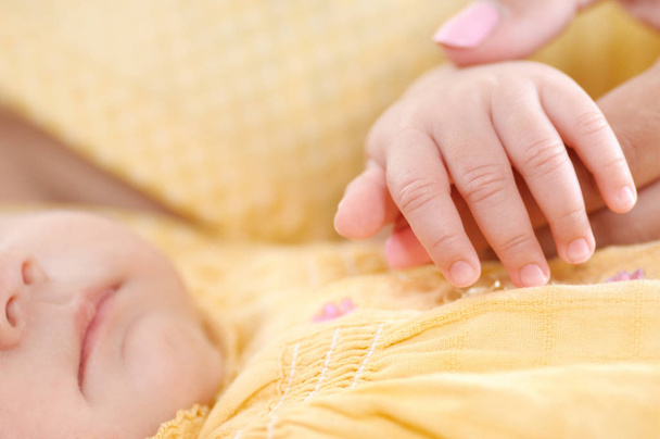 小さな赤ちゃんの手のクローズアップ撮影。母親が赤ん坊の手に触れた思いやりのある概念 - 写真・画像