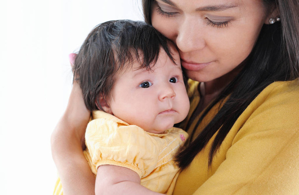 Uma jovem bonita segurando um bebê recém-nascido em seus braços. Conceito de família feliz
. - Foto, Imagem
