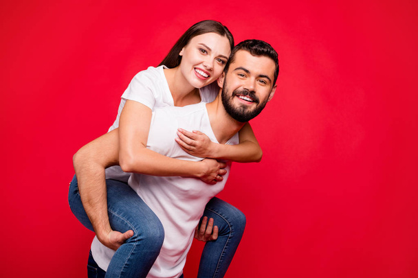 Photo of cheerful cute nice attractive trendy piggyback beautiful handsome couple wearing jeans denim while isolated with red background - Φωτογραφία, εικόνα