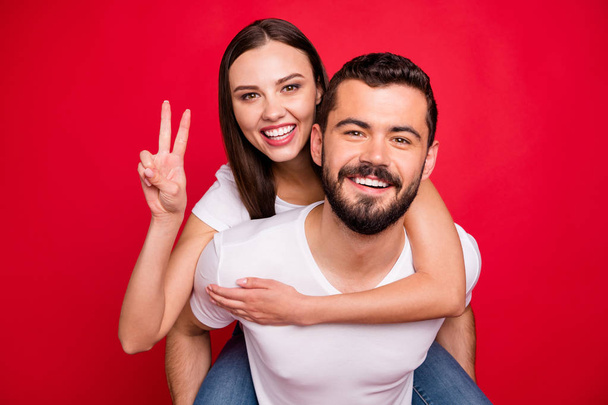 Photo of two funny trendy casual fooling piggyback nice cute people together loving each other wearing jeans denim white t-shirt while isolated over red background - Fotó, kép