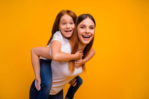 Close-up portrait of two nice attractive lovely cheerful cheery playful person mommy having fun free time piggy backing isolated over bright vivid shine yellow background - Valokuva, kuva