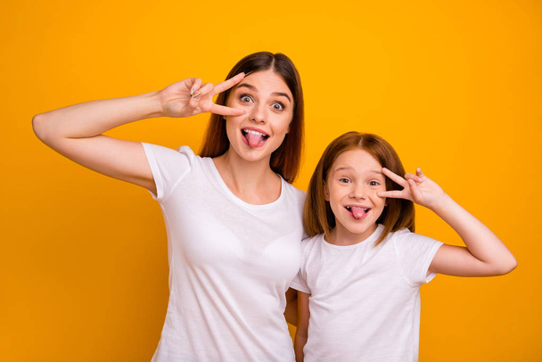 Portrait of two nice attractive lovely comic crazy childish cheerful cheery glad positive person showing v-sign having fun fooling isolated over bright vivid shine yellow background - Fotoğraf, Görsel