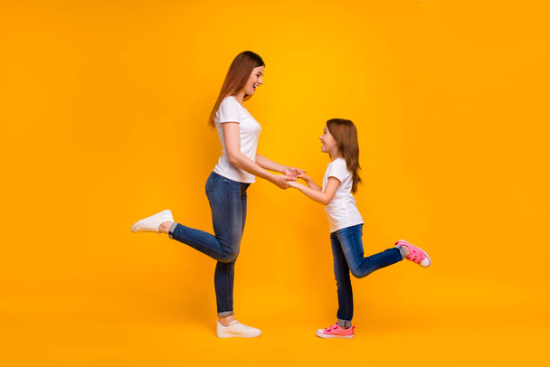 Full length profile side photo of pretty mom with her kid having long hairstyle smiling wearing white t-shirt isolated over yellow background - Foto, imagen