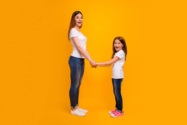Full size profile side photo of impressed mom holding her child having long foxy hairstyle screaming wearing white t-shirt isolated over yellow background - Foto, afbeelding