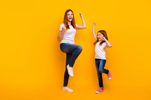 Full size photo of cheerful people with long hair raising fists screaming yeah wearing white t-shirt isolated over yellow background - Fotoğraf, Görsel