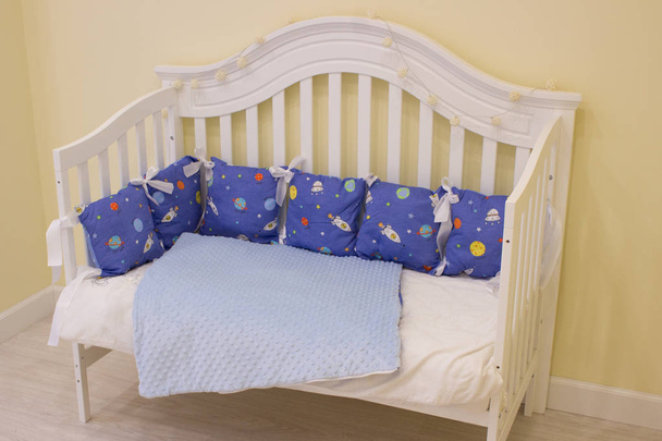 textiles for newborns in the photo Studio in the interior of the nursery, side pillow in the crib, blankets turn into envelopes for walking, cocoon for a comfortable and safe sleep, baskets for toys - Fotó, kép
