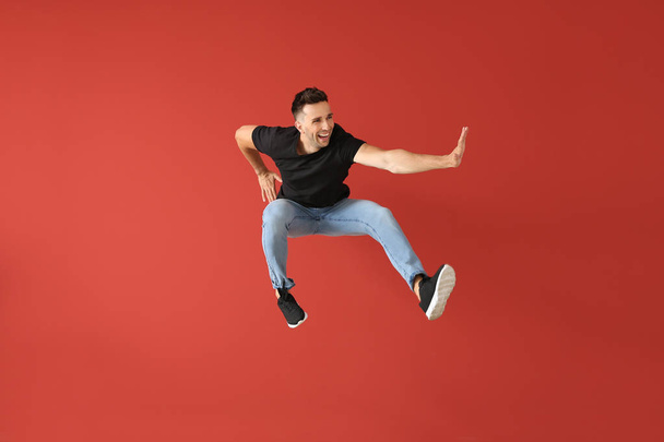 Knappe Jumping jonge man tegen kleur achtergrond - Foto, afbeelding