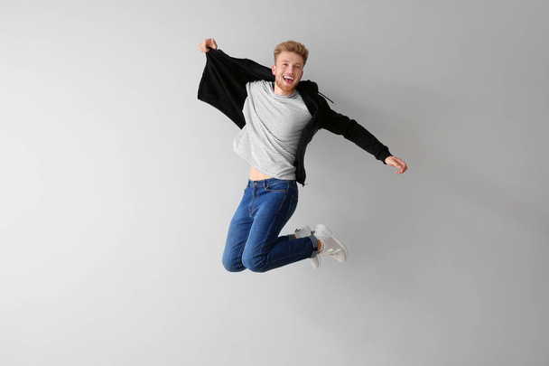 Handsome jumping young man against light background - Foto, afbeelding