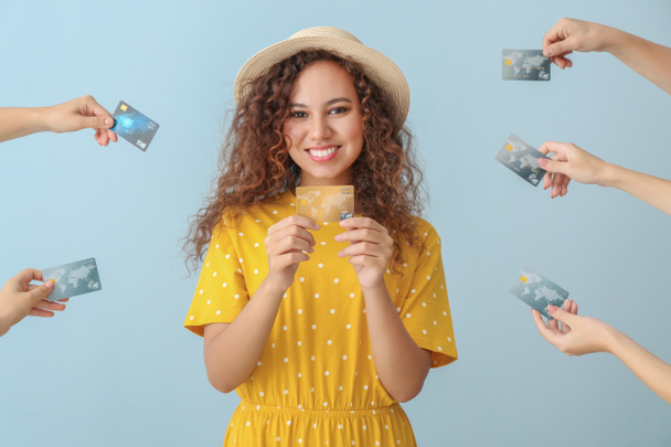 Νεαρή αφροαμερικάνικη γυναίκα και τα χέρια με πιστωτικές κάρτες στο φόντο χρώμα - Φωτογραφία, εικόνα