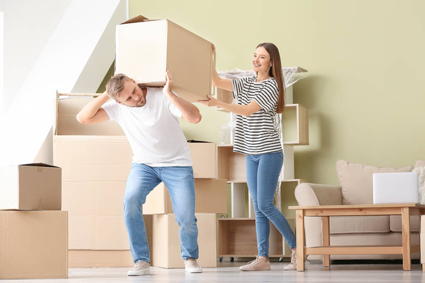 Jeune couple portant des boîtes après avoir déménagé dans une nouvelle maison
 - Photo, image