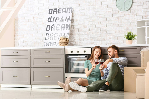 Happy young couple drinking wine after moving into new house - Photo, image