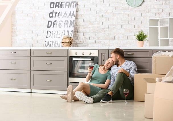 Happy young couple drinking wine after moving into new house - Photo, Image