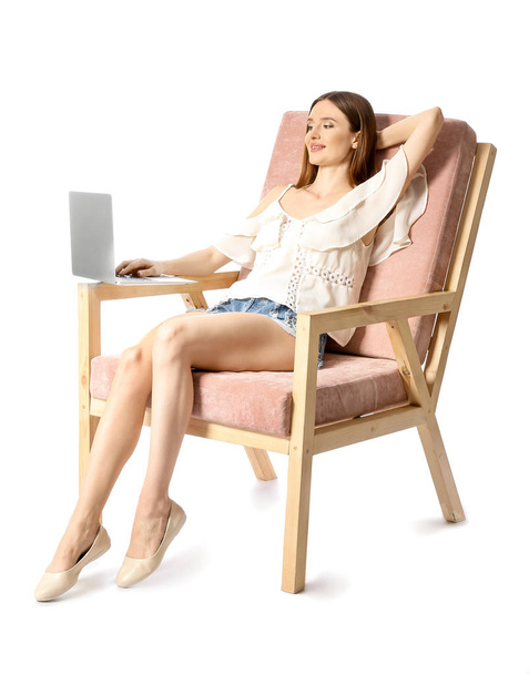 Giovane donna con computer portatile rilassante in poltrona sullo sfondo bianco
 - Foto, immagini