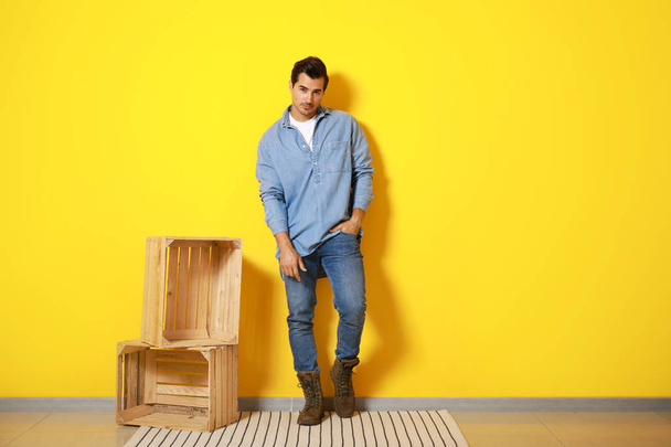 Stylowy modny człowiek i drewniane pudełka z kolorową ścianą - Zdjęcie, obraz