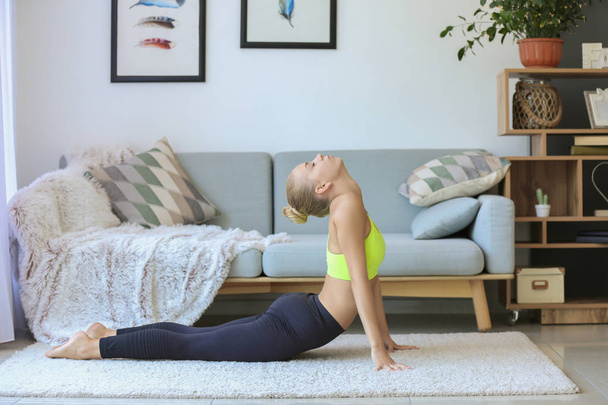 Junge Frau praktiziert Yoga zu Hause - Foto, Bild