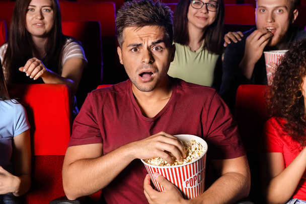 Emotionele man met popcorn kijken film in de bioscoop - Foto, afbeelding