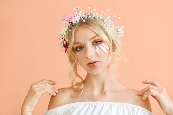 色の背景上の花の花輪と美しい若い女性 - 写真・画像
