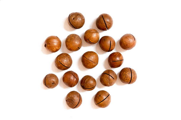 Pattern of nuts- inshell macadamia nut on a white background in the form of a circle. Concepts about decoration, healthy eating and food background. - Foto, Imagen