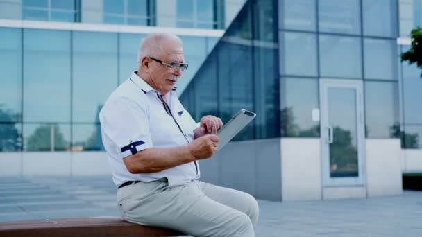 mature man with tablet sits on bench at modern office center - Felvétel, videó
