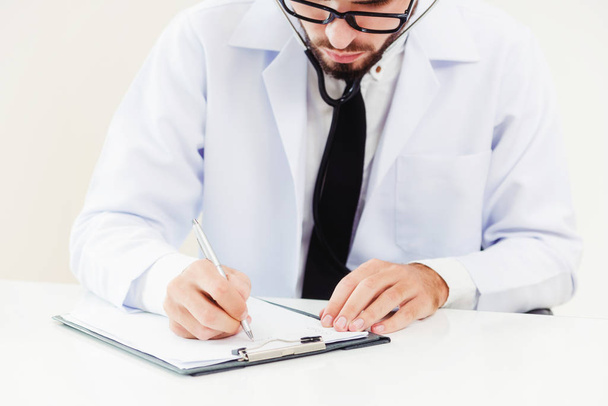 Médico en el hospital escribiendo en un documento en papel
. - Foto, imagen