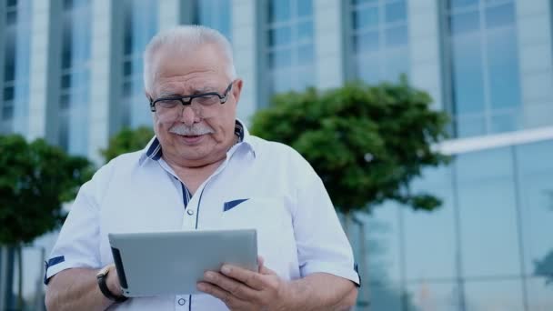pensioner uses tablet against office building in downtown - Video