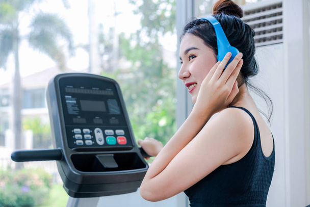 Woman runner listens to music and runs treadmill. - Photo, Image