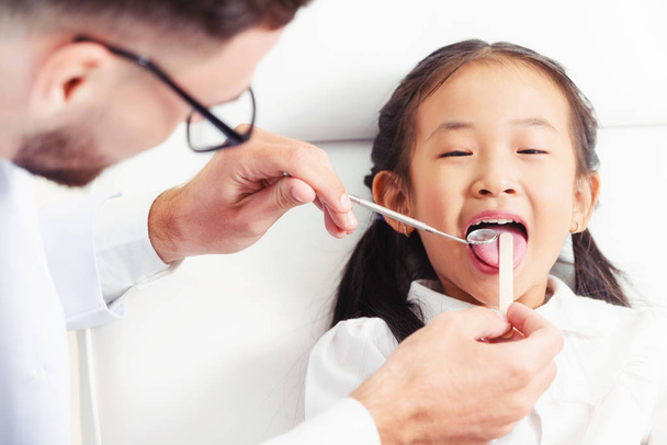 Стоматолог вивчає зуби дитини в стоматологічній клініці
. - Фото, зображення