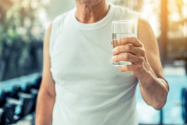 Starszy mężczyzna pić wodę mineralną w centrum fitness. - Zdjęcie, obraz