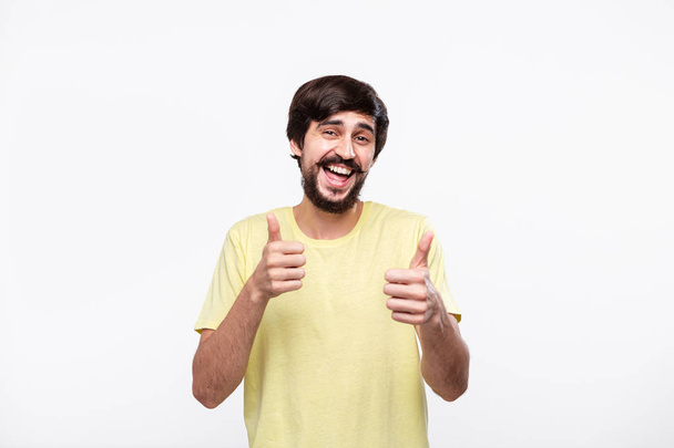 Happy brunet bearded man with moustaches holding two hands with thumbs up. Concept of approval. - Photo, Image