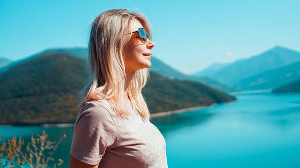 Smiling woman against mountain landscape and lake - Photo, Image