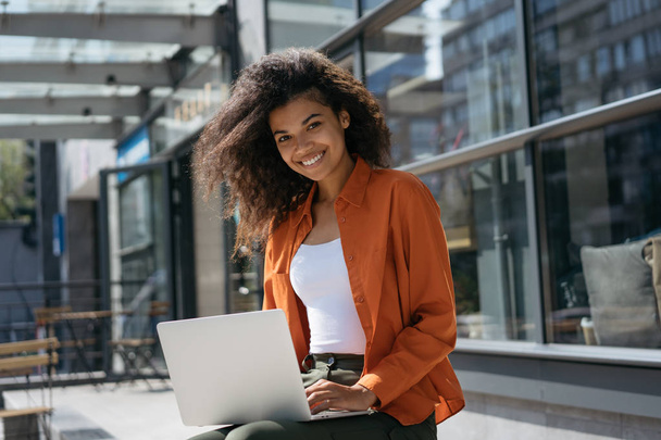 Portret pięknej Afryki amerykańskiej bizneswoman za pomocą laptopa i Internetu, wpisując na klawiaturze. Udany biznes i kariera. Uśmiechnięta kobieta copywriter pracy freelance projektu na zewnątrz - Zdjęcie, obraz