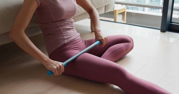 Woman use of roller stick on thigh to release pain at home - Valokuva, kuva
