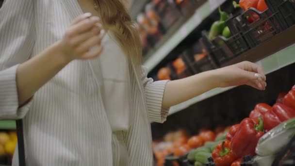 Frau kauft Paprika im Supermarkt. weibliche Hand wählt Bio-Gemüse im Lebensmittelgeschäft. Zero Waste Shopping und gesundes Lebensstil-Konzept. Zeitlupe. - Filmmaterial, Video