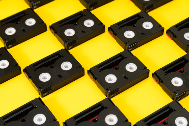 Vintage Mini DV kazetták, használt forgatás vissza egy nap. Műanyag videoszalagok mintázata sárga háttérrel - Fotó, kép