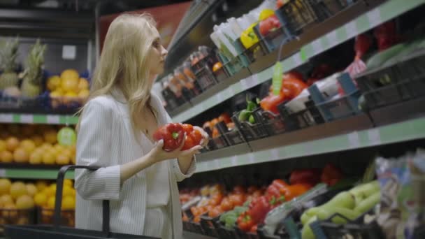 Nainen ostaa Red Pepperiä supermarketista. Naisen käsin valitsemalla luomuvihanneksia ruokakaupassa. Nolla tuhlausta ostoksia ja terveellisiä elämäntapoja käsite. Hidastus
. - Materiaali, video
