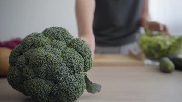 Female hands putting lettuce in deep bowl then taking broccoli and start cutting. Unrecognizable woman cooking breakfast in the kitchen. Healthy lifestyle. Profession of nutraceutical, nutritionist - Video