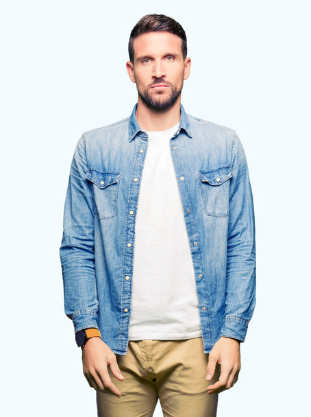 Handsome man with blue eyes and beard wearing denim jacket Relaxed with serious expression on face. Simple and natural looking at the camera. - Photo, Image