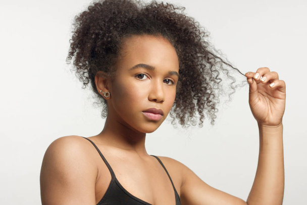 close up retrato s de jovem modelo de raça mista com cabelo encaracolado em estúdio com maquiagem neutra natural
 - Foto, Imagem