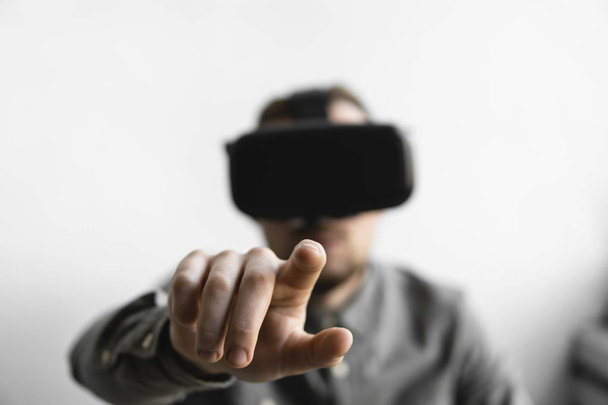 Young bearded man with virtual reality glasses trying to touch something or tap some thing in front of what he seeing. Modern technologies. The concept of future technology. - Foto, Imagen