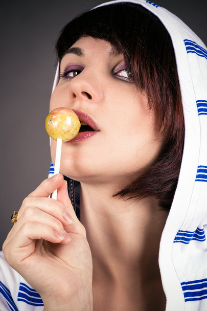 Woman isolated on gray background licking lollipop - Foto, afbeelding