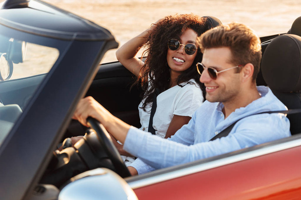 Beautiful young multiethnic couple riding in a convertible - Photo, Image