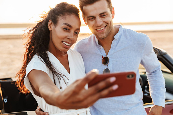 Photo of happy multiethnic couple taking selfie photo on smartph - 写真・画像