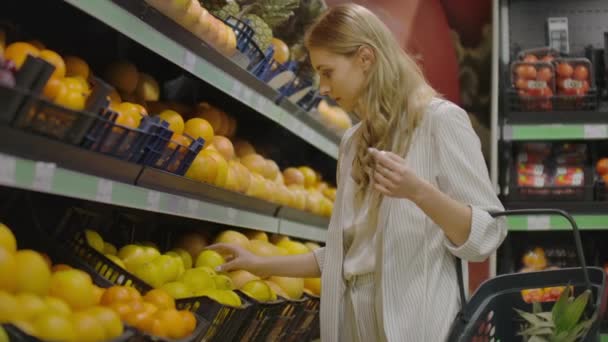Frau pflückt Zitronen im Lebensmittelladen am Obst- und Gemüsegang eines Supermarktes. - Filmmaterial, Video