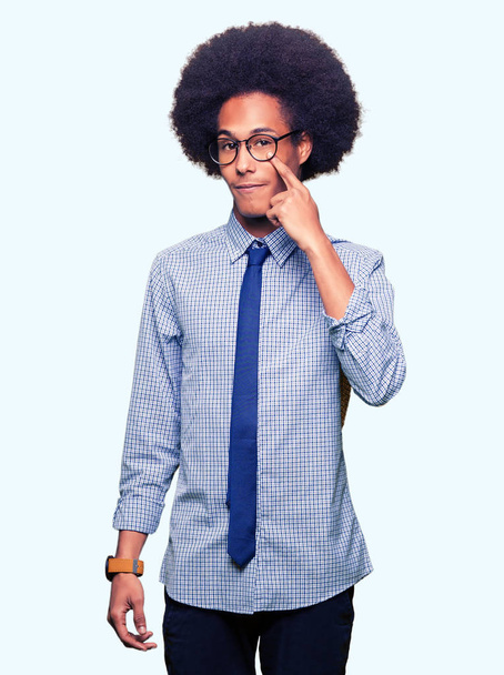 junger afrikanisch-amerikanischer Geschäftsmann mit Afro-Haaren, Brille, die auf das Auge zeigt, das dich beobachtet, Geste, misstrauischer Ausdruck - Foto, Bild
